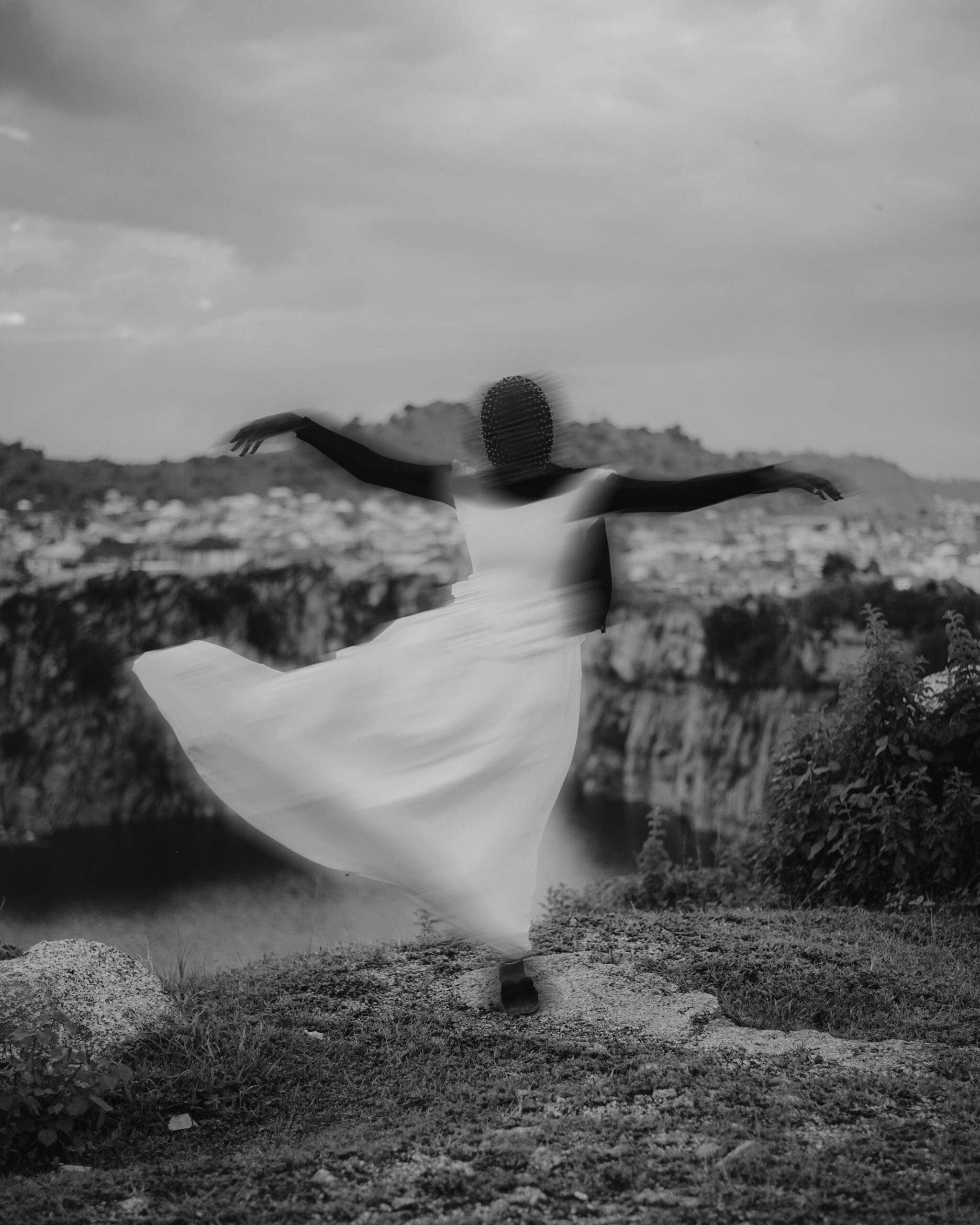 Blurred figure dancing near a cliff, captured in black and white for a timeless feel.